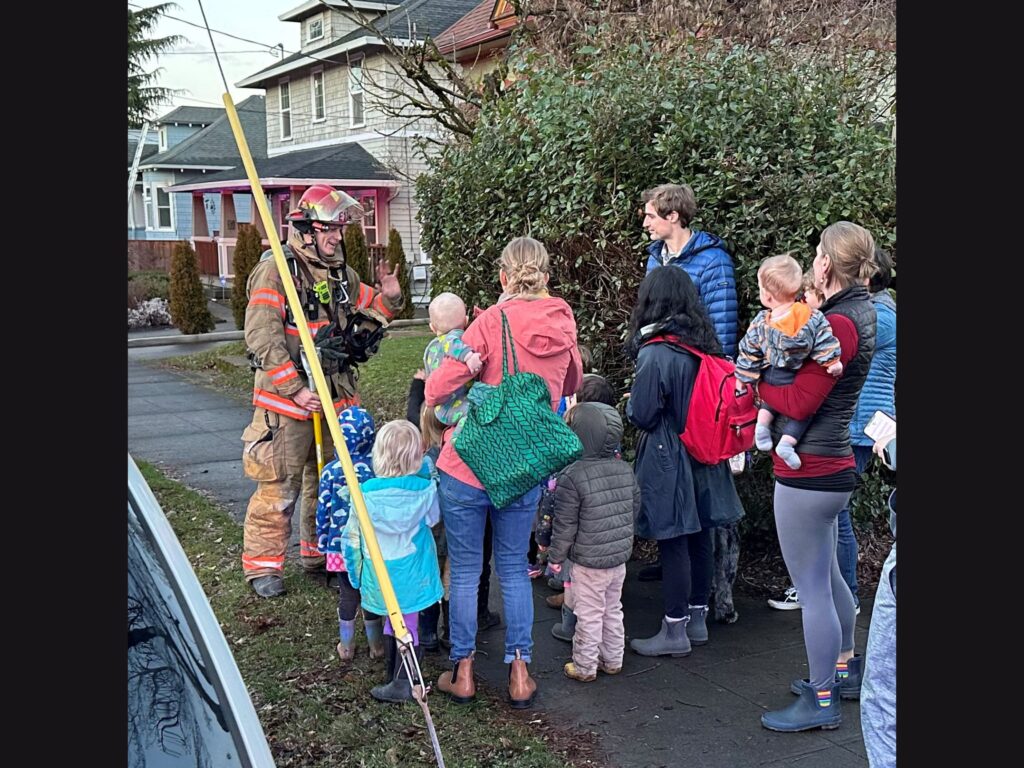 a firefighter providing a lesson in fire safety to the neighborhood children